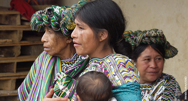 One elderly woman, one middle-aged woman, and a younger woman holding a baby in Guatemala.