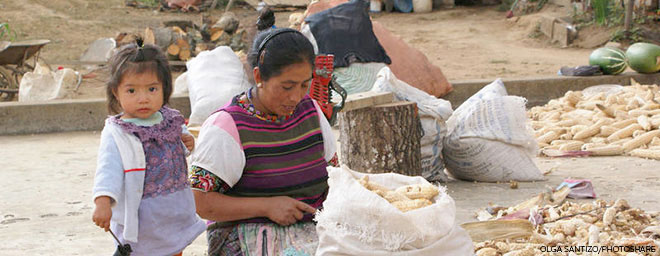 A woman prepares corn as a young child watches in Patzún, Chimaltenango, Guatemala.