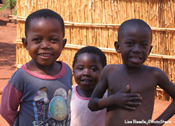 Three smiling children outside.