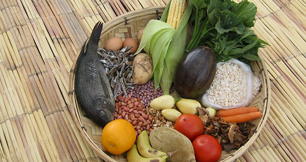 Basket full of variety of foods like fish, grains, and leafy vegetables.