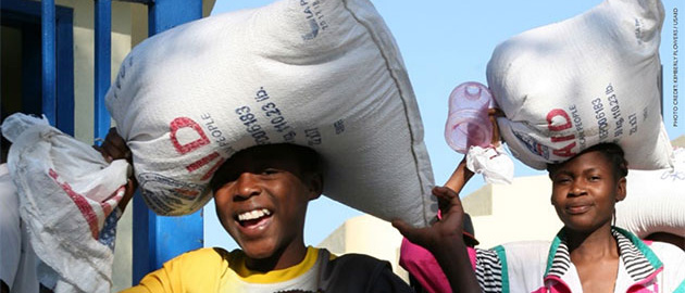 Two women carry bags of supplies on their heads. 