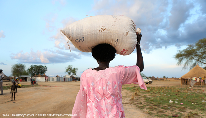 woman carrying bag of supplies on head