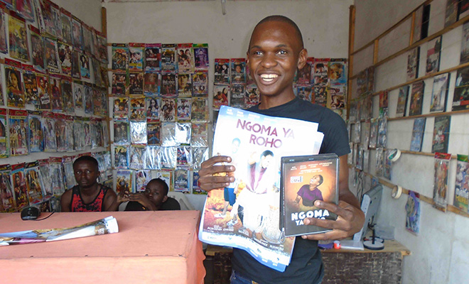 movie vendor holding Ngoma Ya Roho poster and DVD