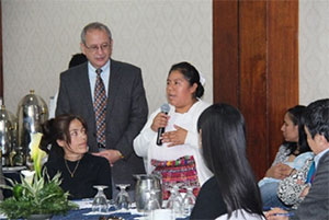 woman speaks into a microphone to a group