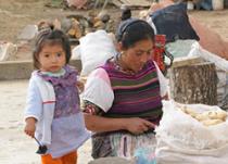 A woman prepares corn as a young child watches in Patzún, Chimaltenango, Guatemala.