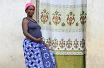 pregnant woman stands in front of home entrance